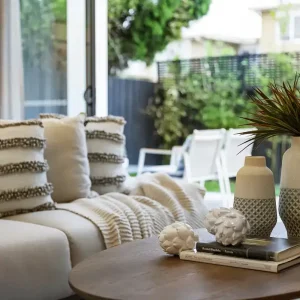 Soggiorno luminoso con divano e accessori decorativi per home staging