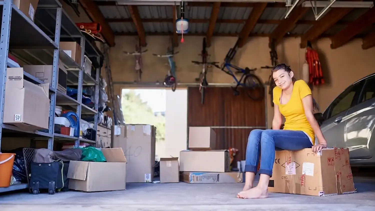 organizzare-garage-stoccaggio-ordine-cover Donna seduta su scatola in garage ordinato